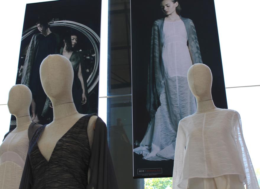 Fashion display with mannequins in textured garments and large posters of models wearing similar styles.