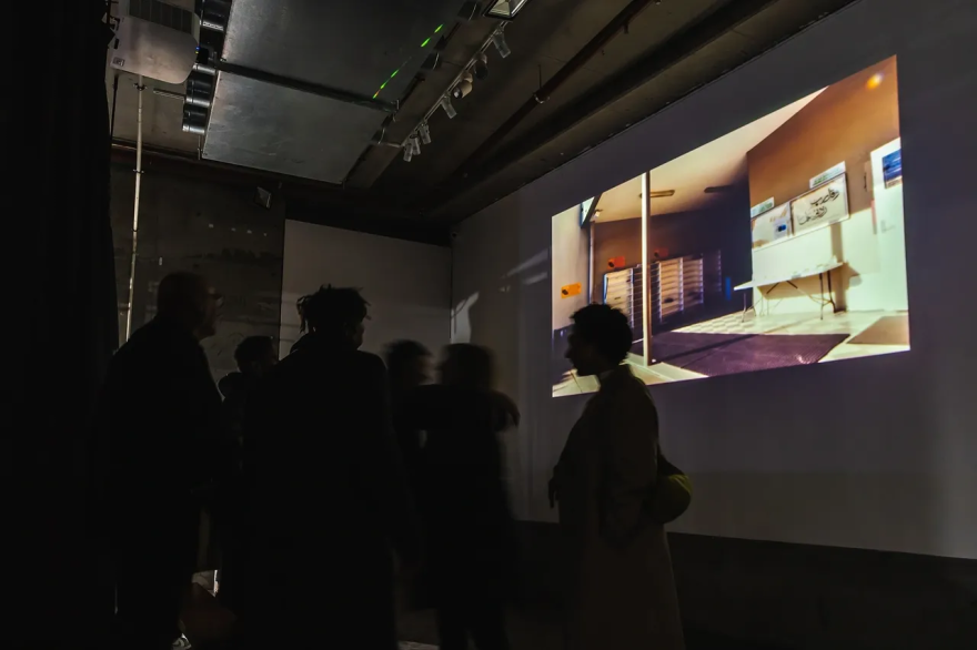 People watching a projected image in a dimly lit room.