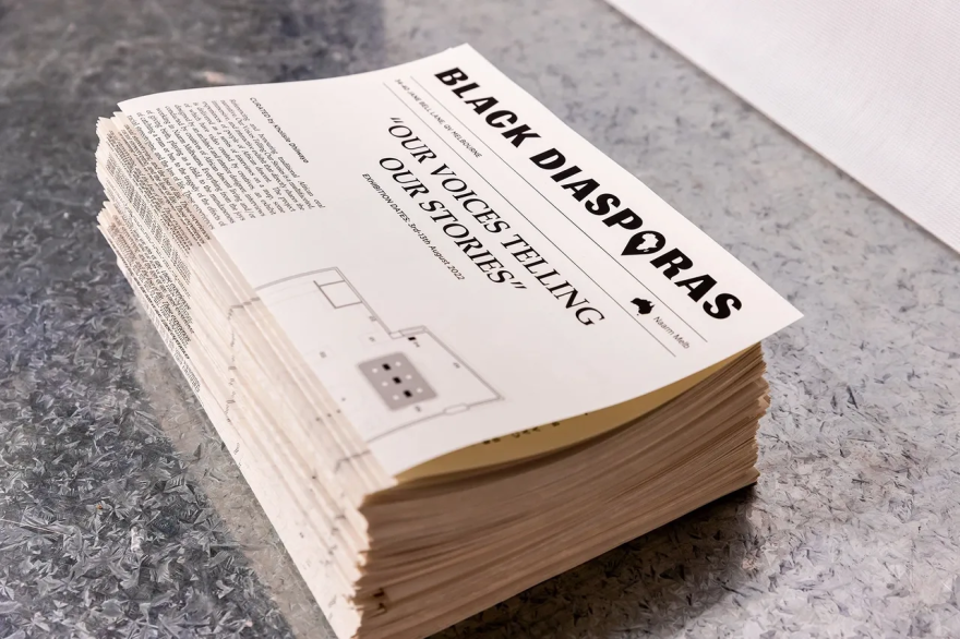 A stack of printed papers with "BLACK DIASPORAS" and "OUR VOICES TELLING OUR STORIES" on the top page.