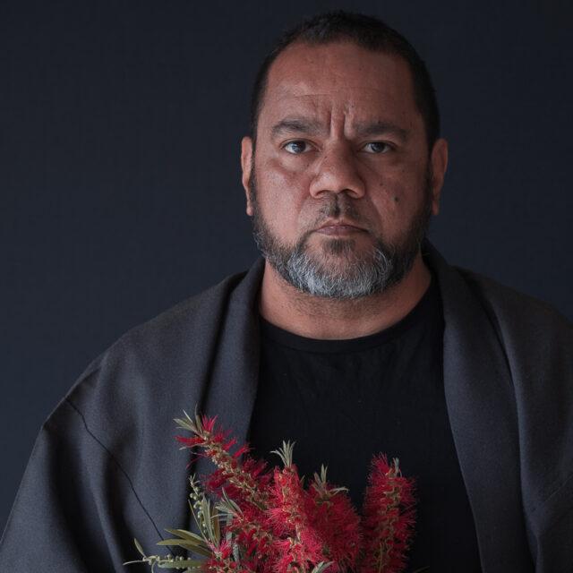 Headshot of Michael Jalaru Torres holding native Australian flowers