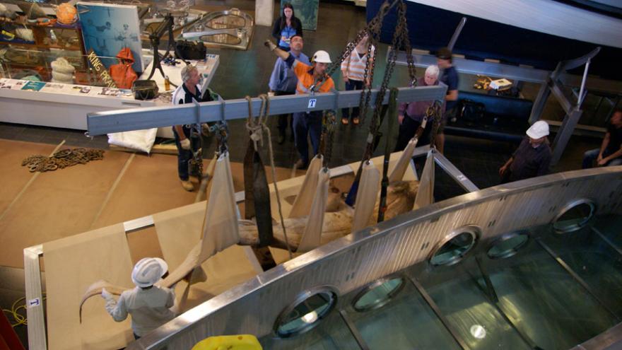 People use chains and slings to lift an object in a museum.