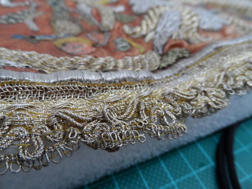 Close-up of intricate embroidery with gold and silver threads on a textile.