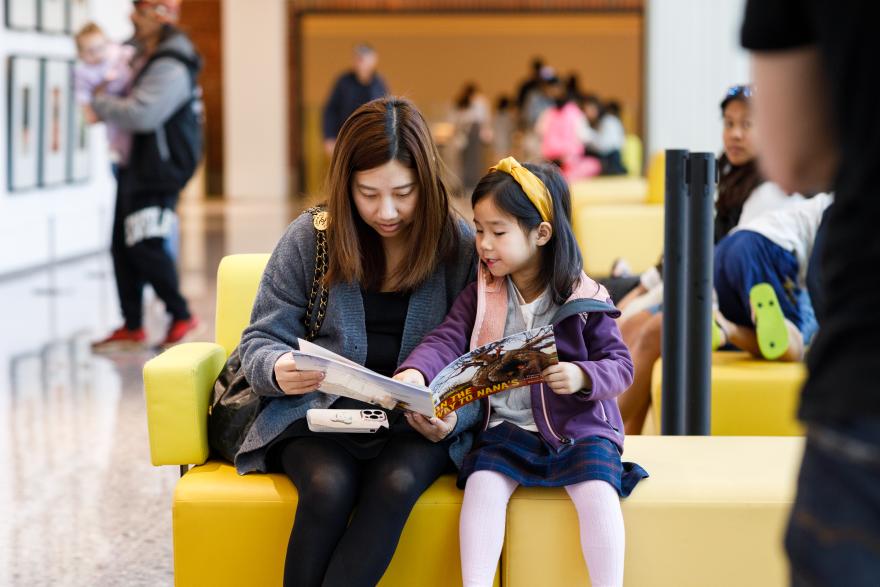 A mother and daughter read a storybook in a Museum gallery