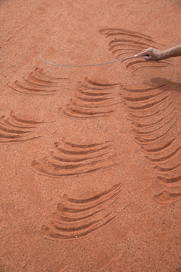 Photograph of a hand drawing lines in the sand