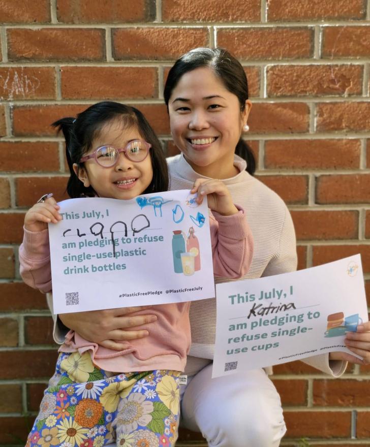 A person and child holding up Plastic Free July pledges
