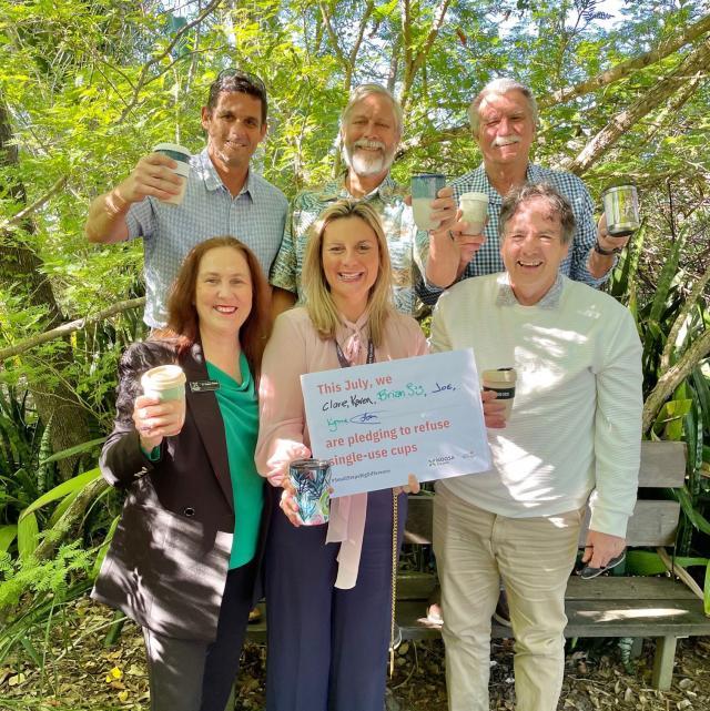 A group of people holding up a Plastic Free July pledge