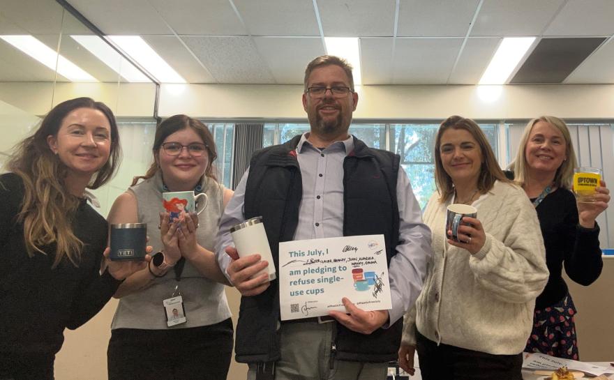 A group of people holding up a Plastic Free July pledge