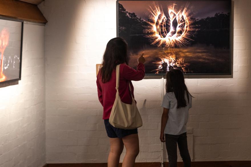 Two people viewing fiery artwork in a gallery.
