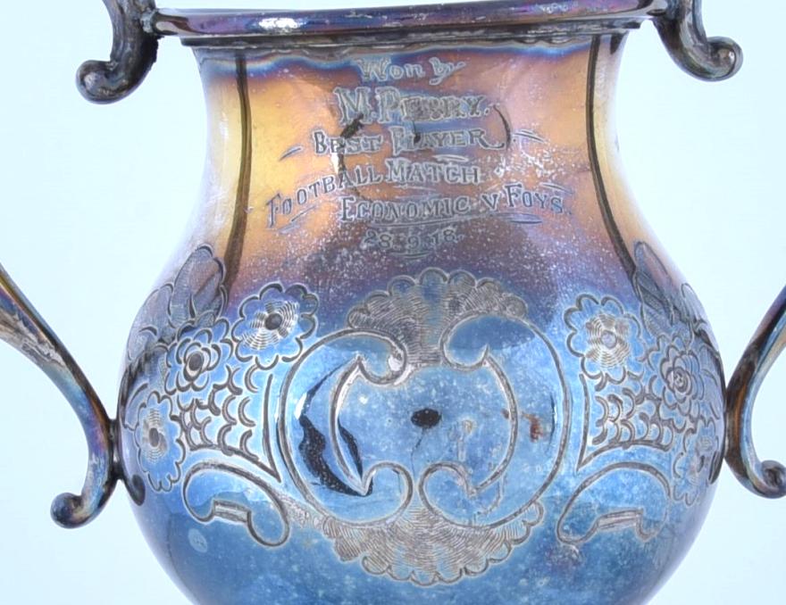 A close-up shot of the trophy engraved with 'Won by M. Perry. Best Player Football Match Economic v Foys.'