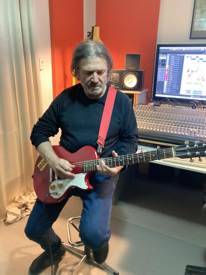 Dom Mariani playing the guitar in his studio