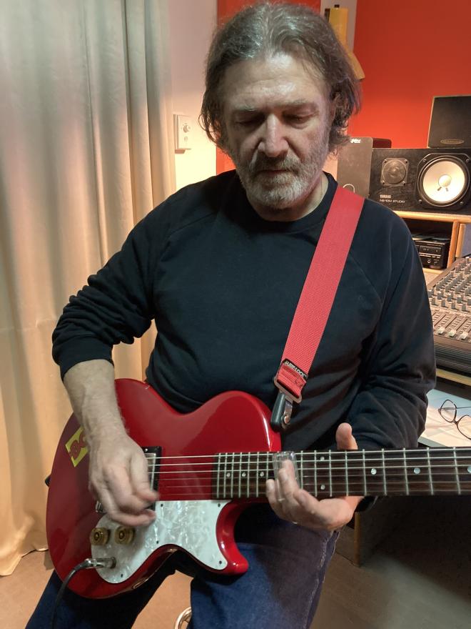 Dom Mariani playing the guitar in his studio