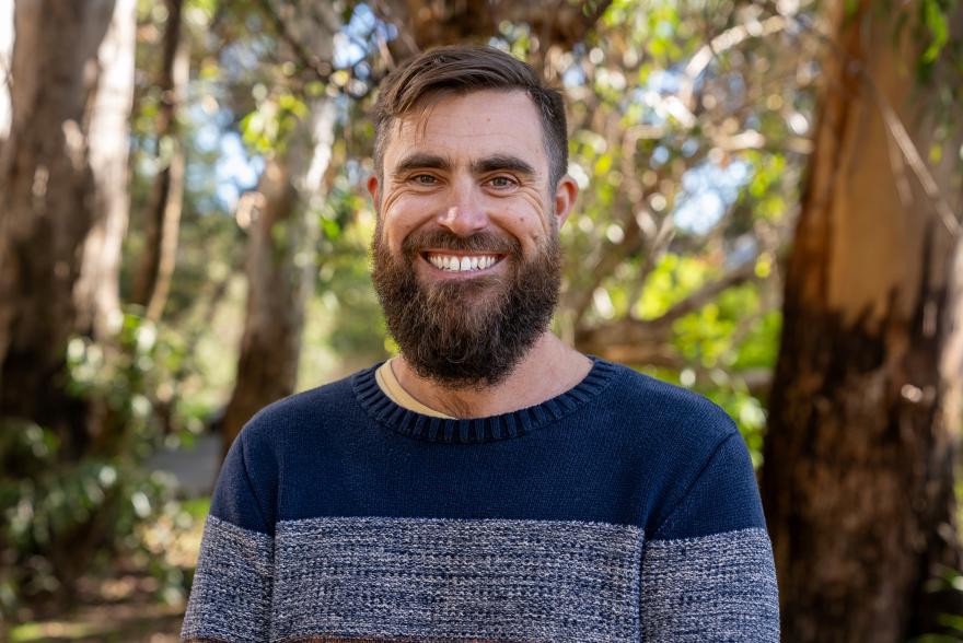 Dr Todd Bond stands and smiles at the camera in a Forrest