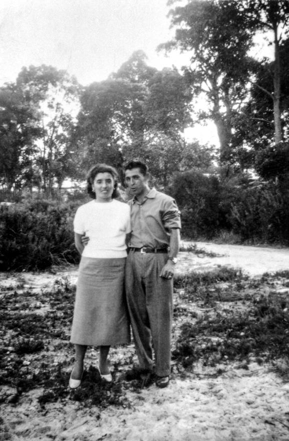 Vintage photograph of a woman in a white shirt and long skirt standing her her husband on the grass.