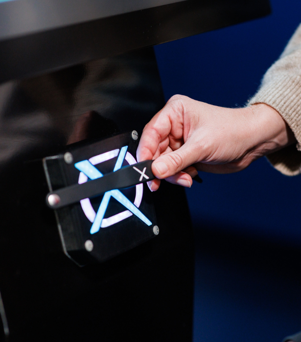 A hand moves a small slider marked with an “X” on a glowing interactive panel display.