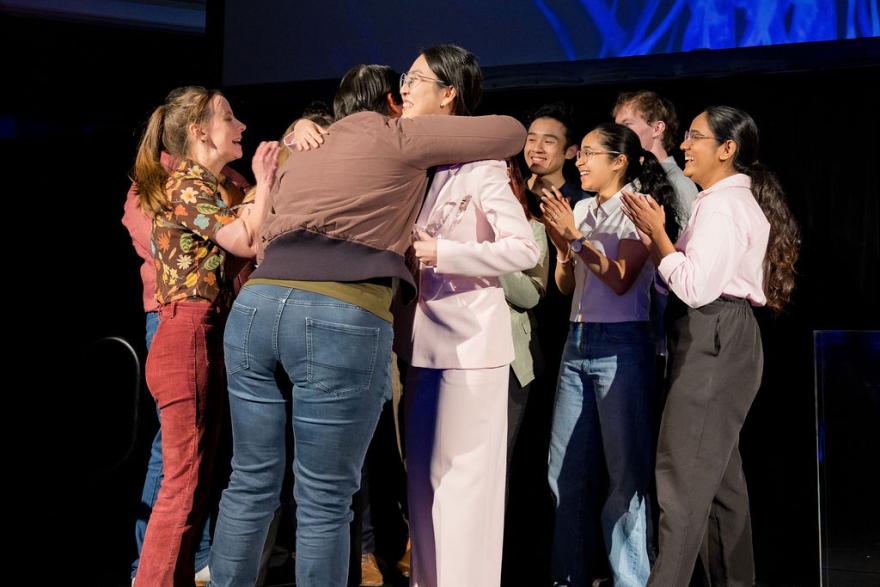 A group of people hugging on stage