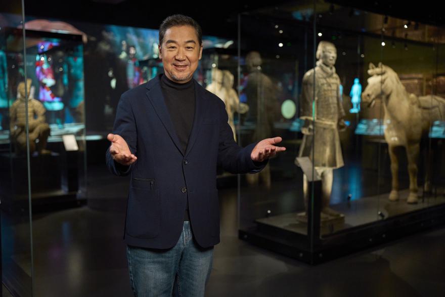 Chinese ambassador Zhang Guoli standing in the Terracotta Warriors gallery with his arms outstretched