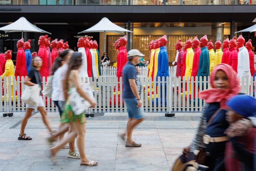 A group of people walking past brightly coloured silk lanterns shaped like Terracotta Warriors