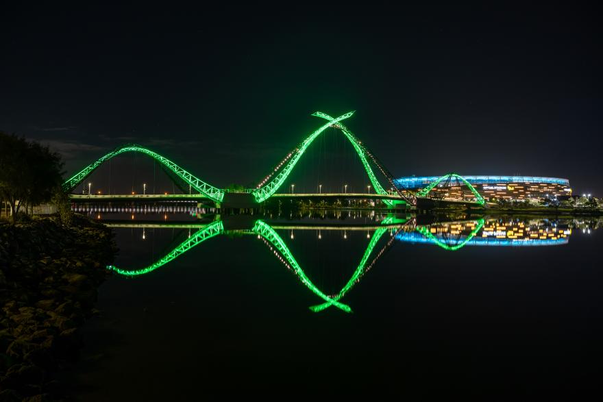 Optus Stadium and the Matagarup bridge lit in jade green