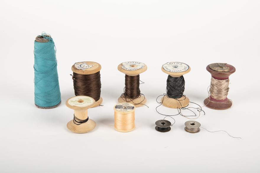 Nine thread spools and bobbins in various colours