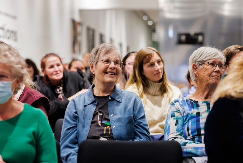 Audience members seated at a public talk, listening attentively in a gallery or museum space.