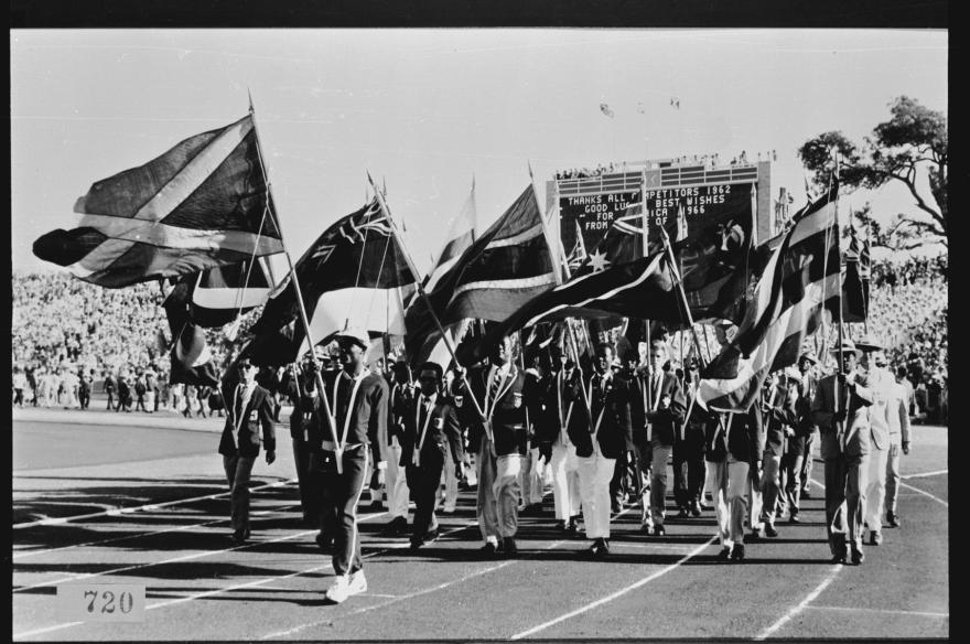 Black and white photograph of flag bearers marching on a track