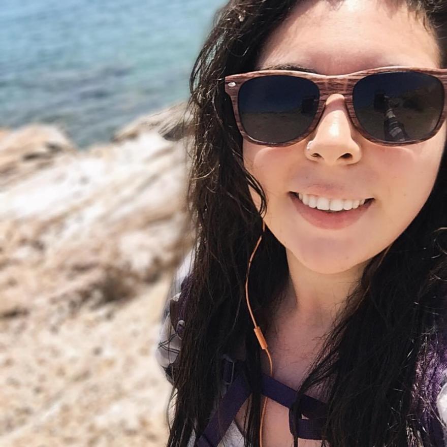 A woman with dark hair and sunglasses at the beach