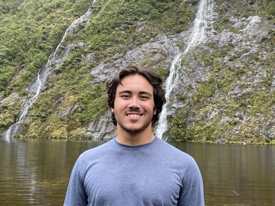 A man in a blue shirt standing in front of water