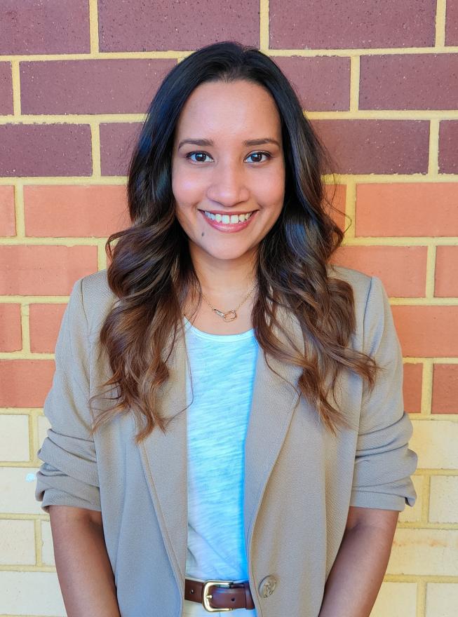 A woman with long brown hair wearing a beige blazer