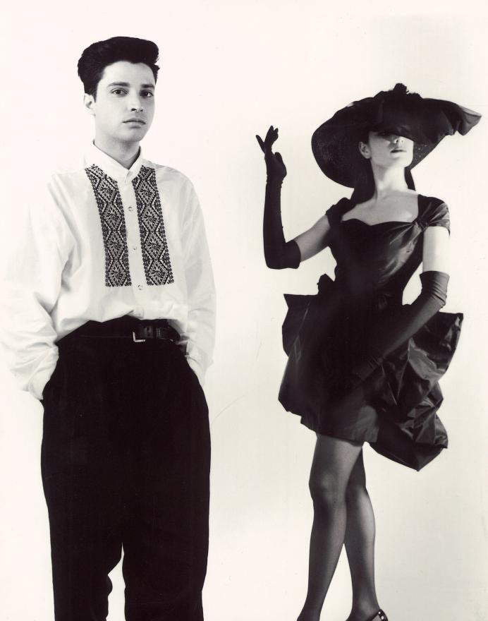 Aurelio Costarella poses next to a model in a wide brimmed black hat, black gloves and black dress
