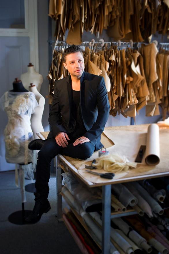 Aurelio Costarella sits on a table in his dressmaking workshop