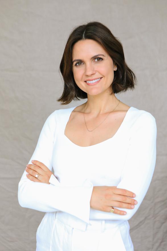 A woman wearing a white shirt and pants with her arms crossed