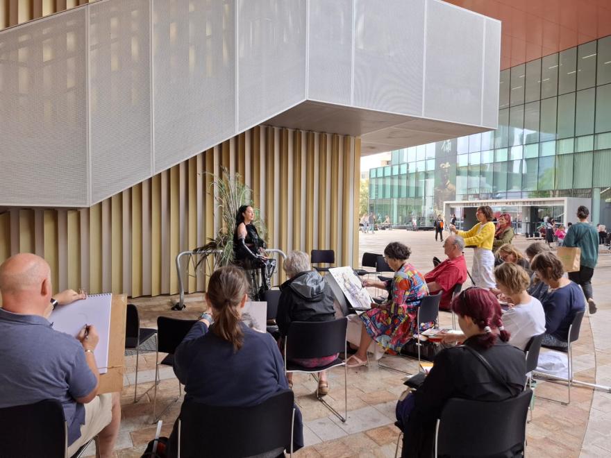 group of people sitting around a model, sketching