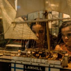 Two children intently examine a model ship in a showcase