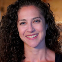 A person with dark curly hair smiling at the camera