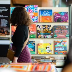An adult looks at a display of brightly-coloured books in a museum gift shop