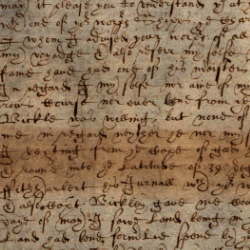 Close-up of an aged handwritten historical manuscript with faded ink, dense cursive text, and visible wear on parchment.