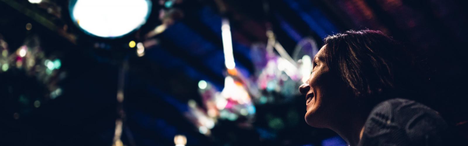 A young woman looking up at a light display on the ceiling.