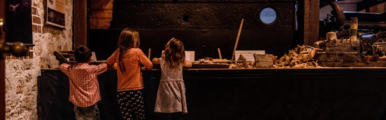 Three children examine a museum display