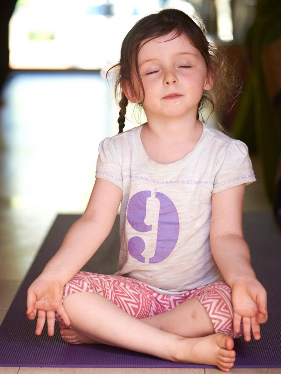 Little girl seating in a yoga position