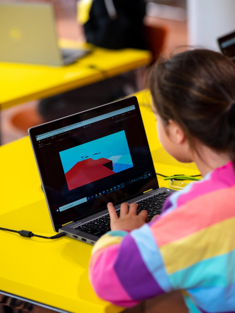 A child building a video game on her laptop