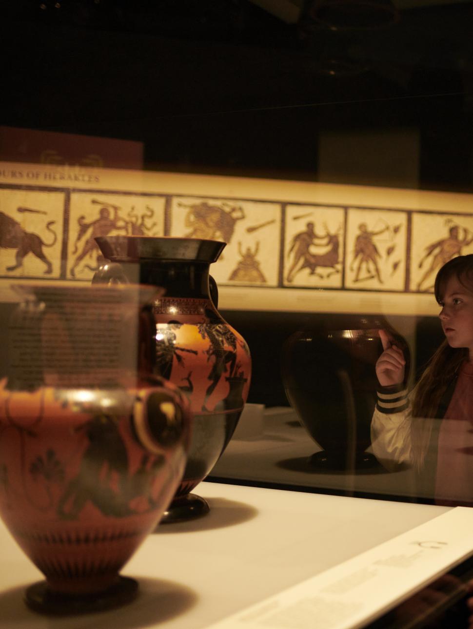 Two girls looking at ancient greek pottery about the Labours of Herakles