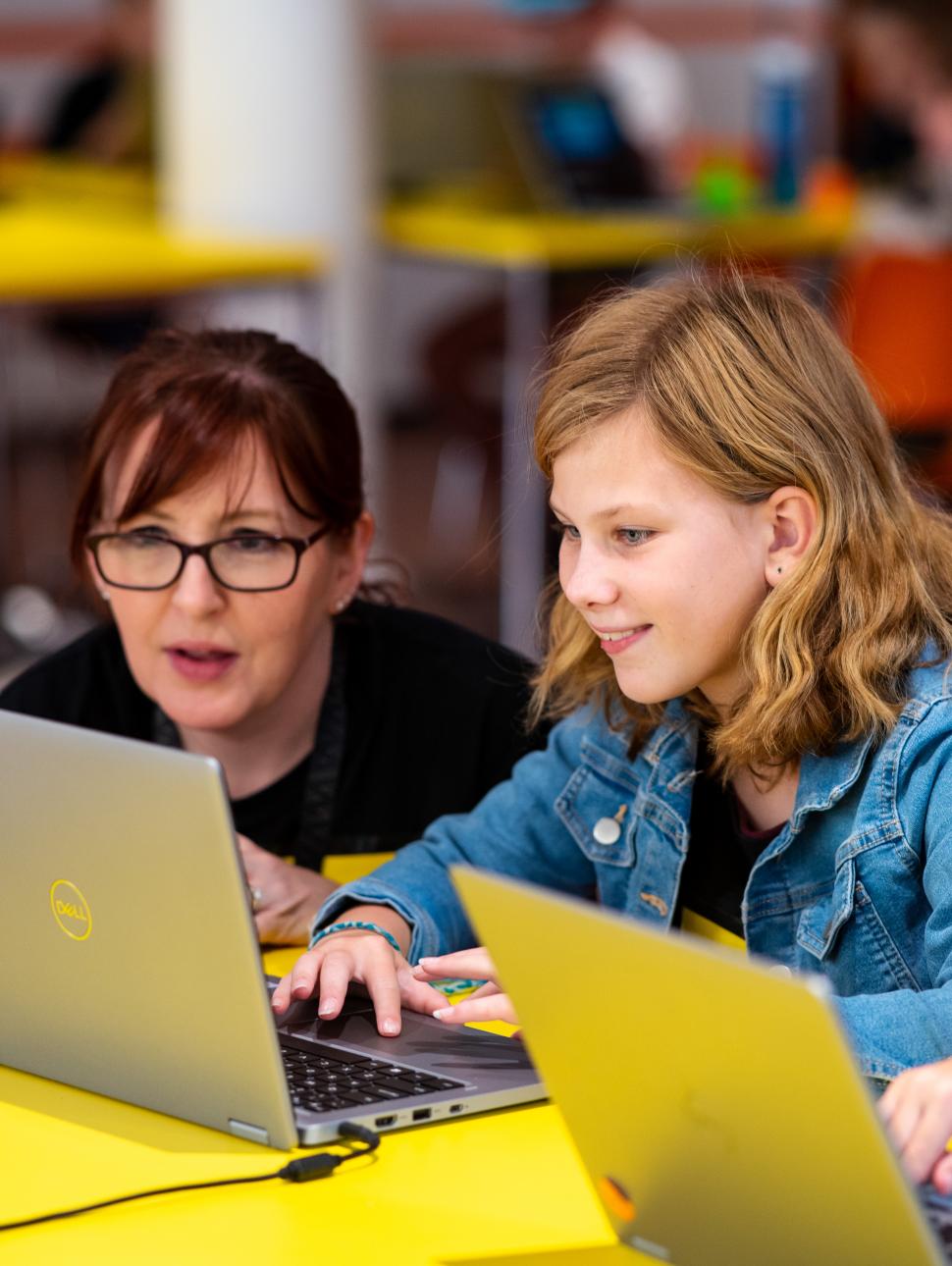 Two children working together on laptops