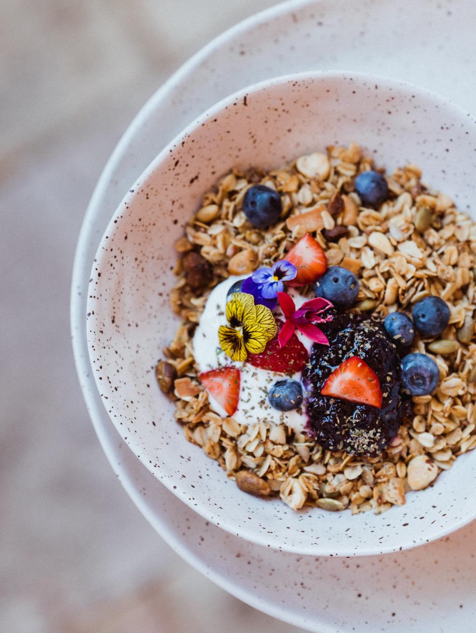 A bowl of granola with fresh strawberries and macadamia