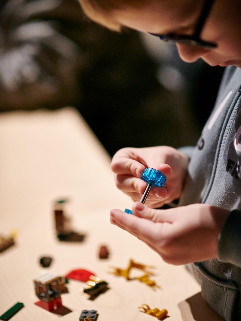 A close-up view of a young child concentrating as they build a LEGO model