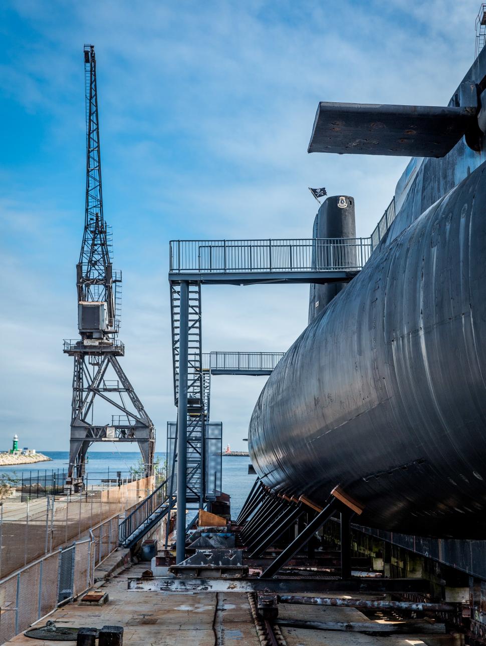 An exterior view of the submarine HMAS Ovens and surrounding slipway beneath a blue sky