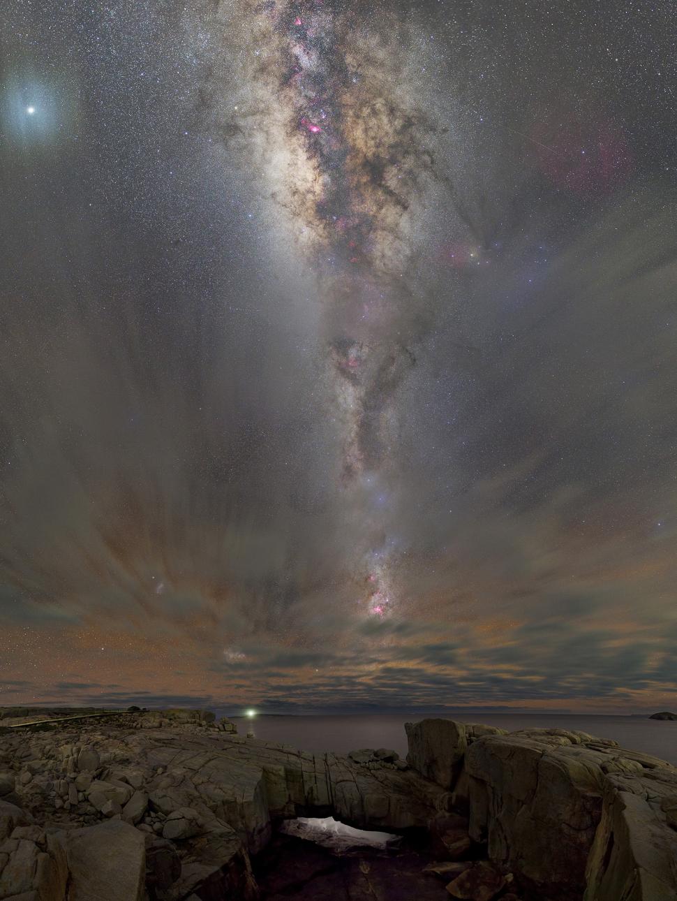 An astrophotograph of a starry night sky above the coast