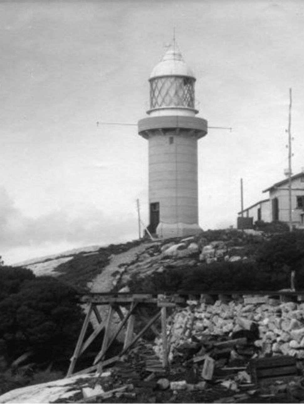 A black and white photograph of a lighthouse on a rocky hill