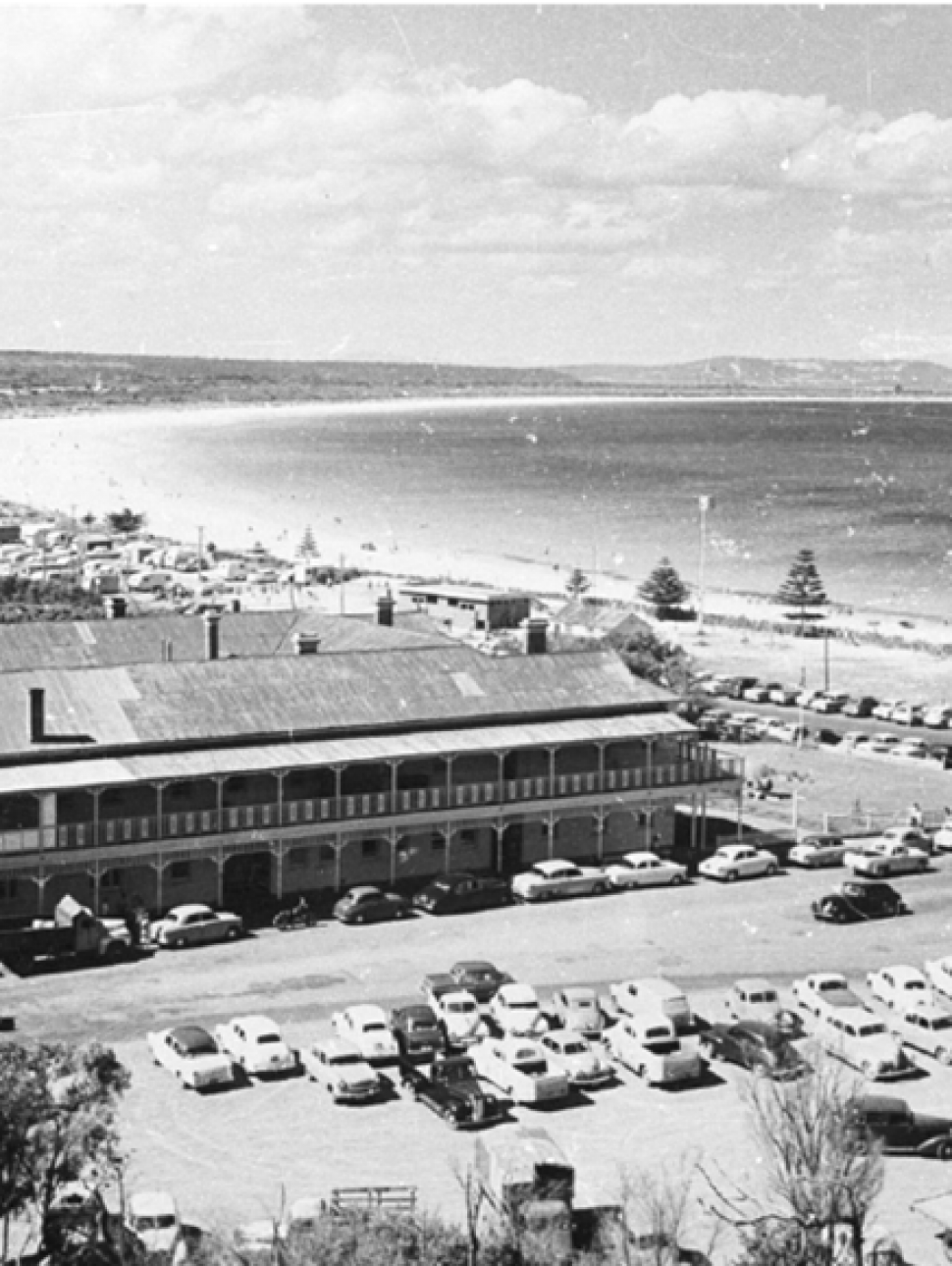 A black and white aerial photograph of a large hotel by the beach