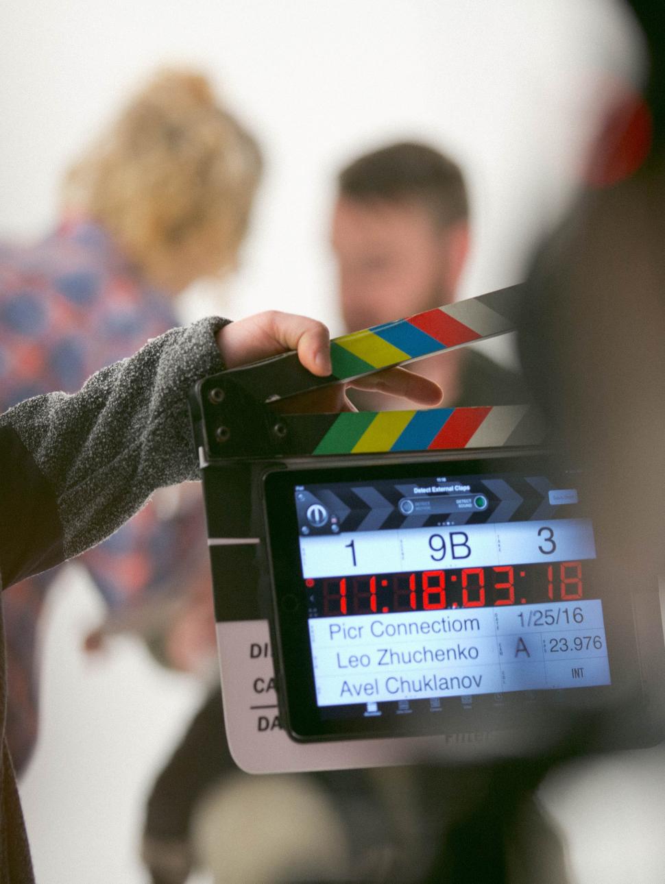 A film director holds a clapboard up in front of two actors