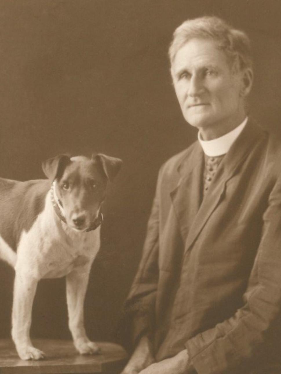 An old sepia toned portrait of a middle-aged man in formal clothing and a small dog